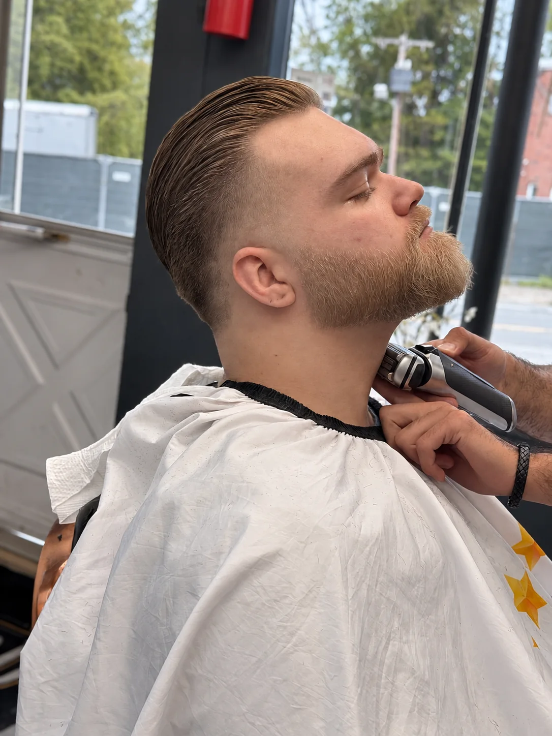 Barber trimming a customer's beard at JR Barbershop