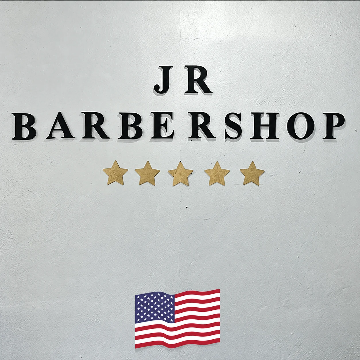 JR Barbershop wall lettering above five gold stars and an American flag graphic