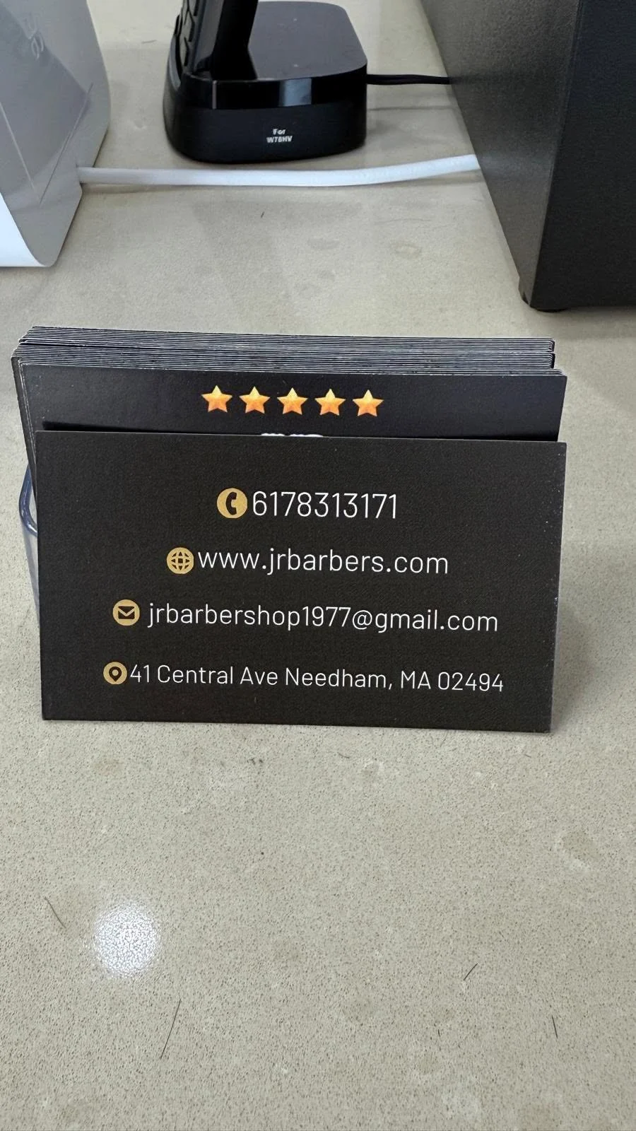 JR Barbershop business cards showing contact details in a counter display