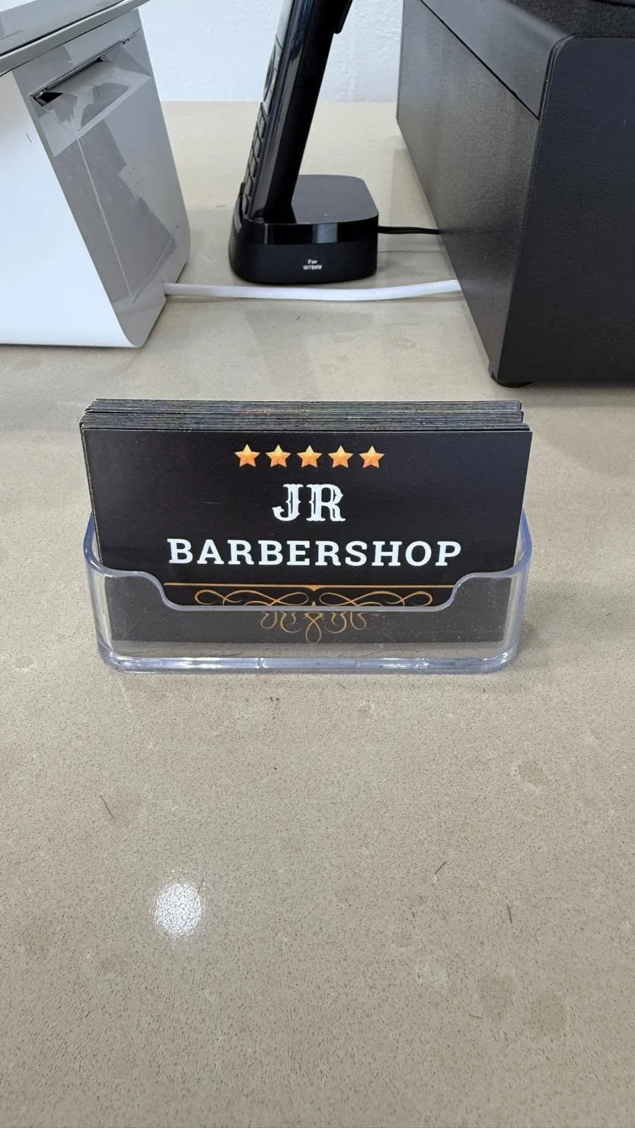 JR Barbershop business cards showing the shop logo in a clear holder