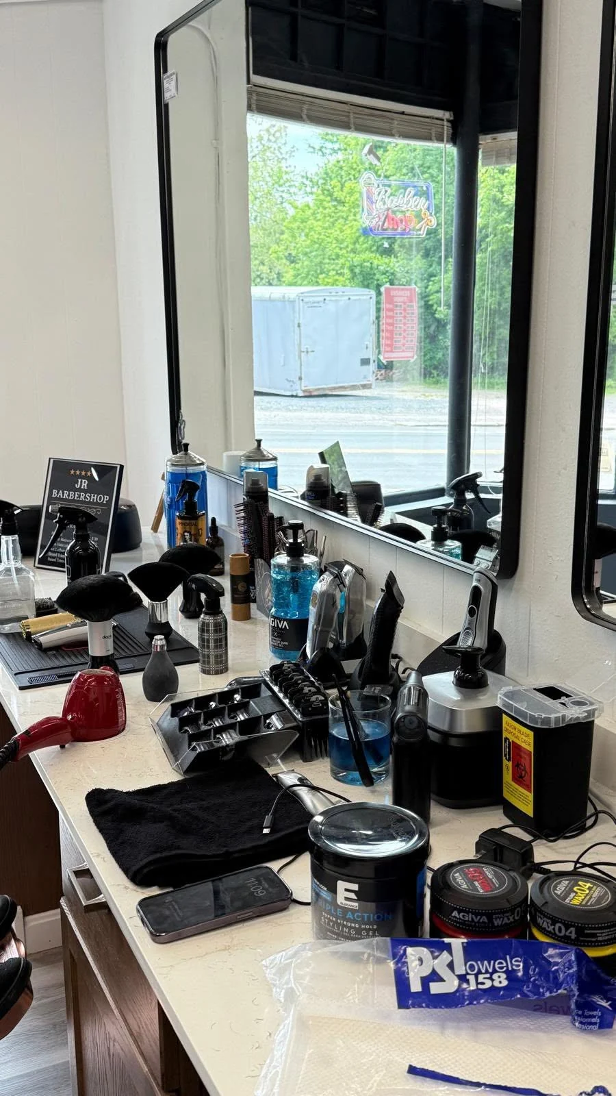 Barber tools and grooming products arranged at a workstation beside the shop window