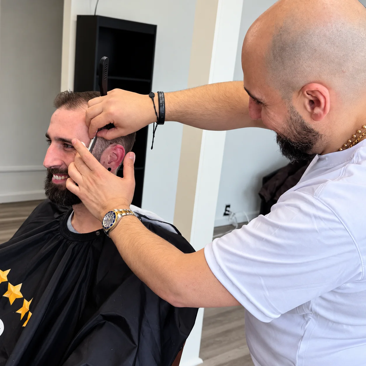 Barber using a straight razor to detail a customer's temple and hairline